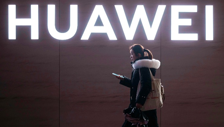 Ciudadana china pasa por delante del logo de Huawei, una de las principales empresas chinas.